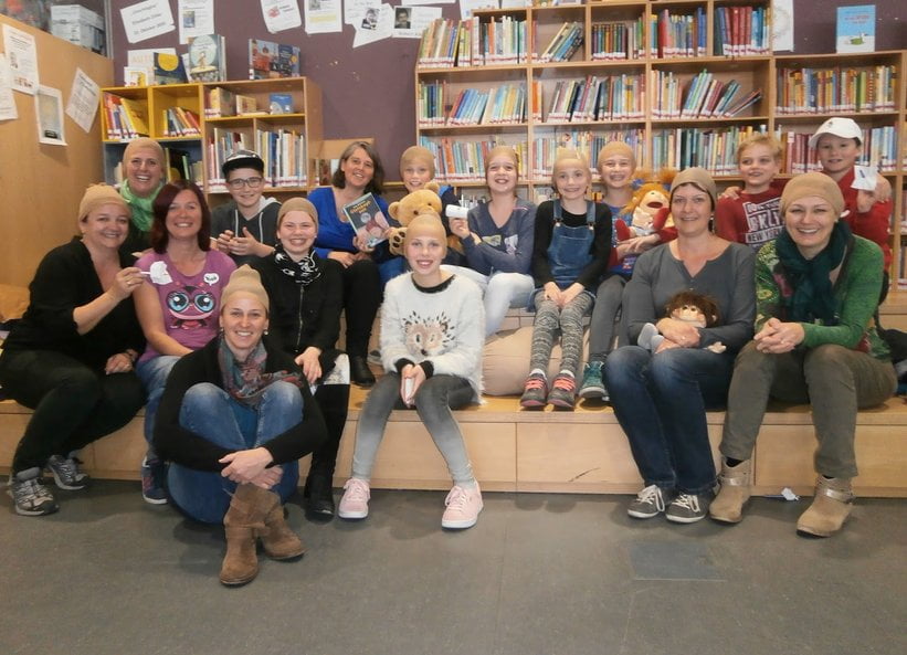 Eine Gruppe aus Kindern und Erwachsenen - mit hautfarbenen Haarnetzen auf den Köpfen - nach einer Lesung aus Petra Hillebrands Buch "Glatzkopfzeit".